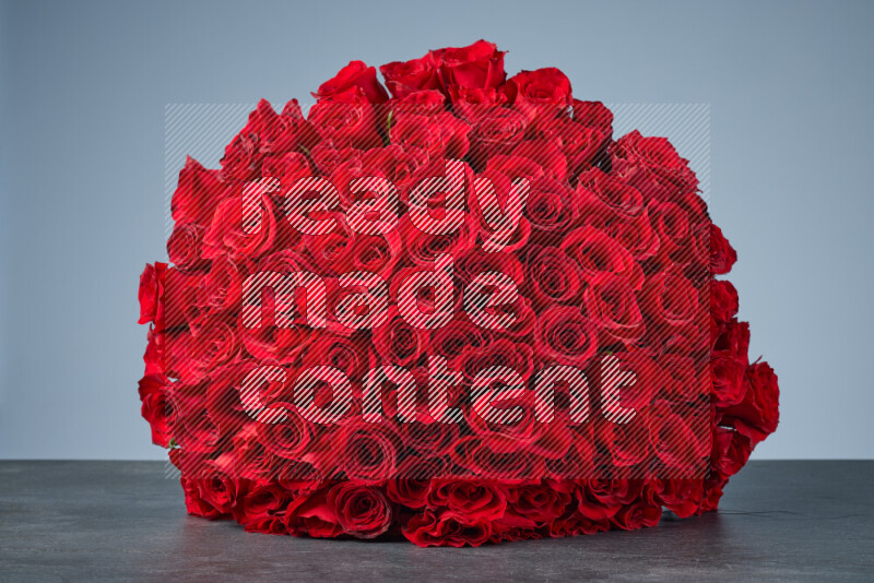 A sphere of vibrant red roses arranged tightly on black marble background