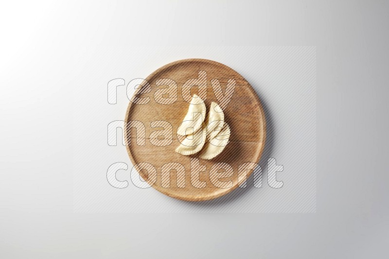 Four Sambosas on a wooden round plate on a white background