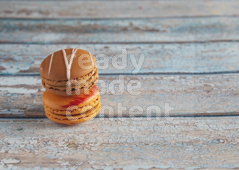45º Shot of of two assorted Brown Irish Cream, and Orange Exotic macarons on light blue background