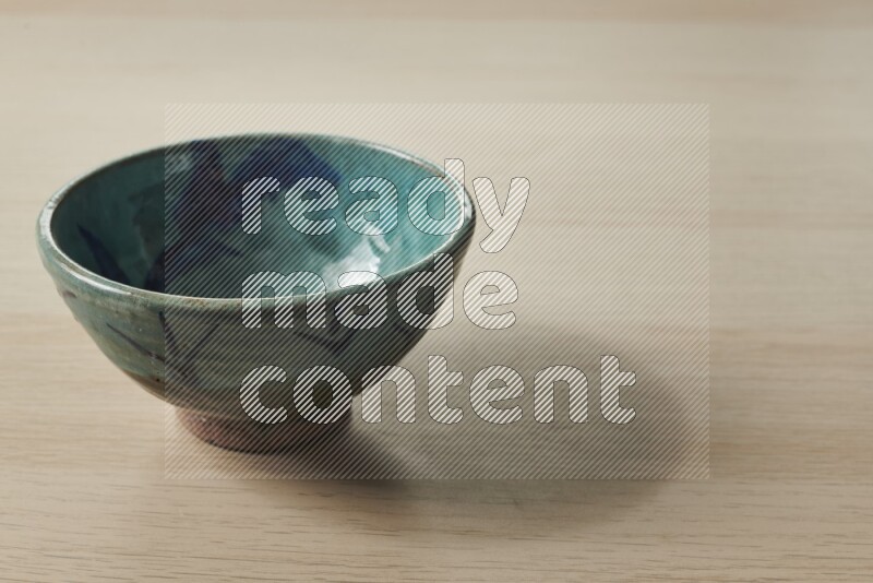 A decorative pottery bowl on light wooden background