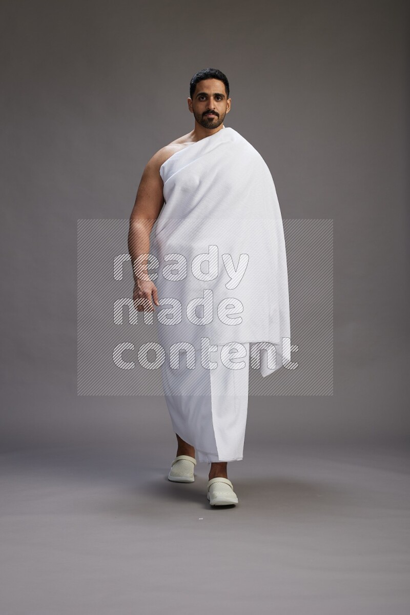 A man wearing Ehram Standing Interacting with the camera on gray background