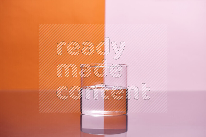 تظهر الصورة أواني زجاجية ممتلئة بالماء موضوعة على خلفية من اللونين البرتقالي والوردي