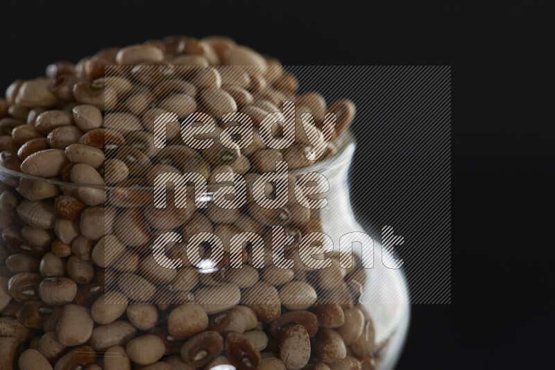 Black-eyed peas in a glass jar on black background