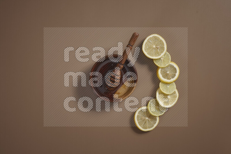 A bowl full of honey with some of citrus fruits such as lemon and orange on a beige background