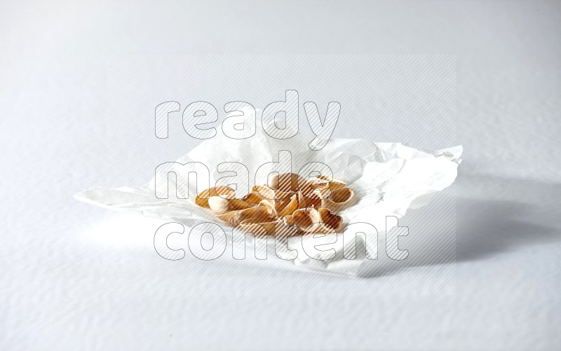 Pistachio peels on a crumpled piece of paper on a white background in different angles