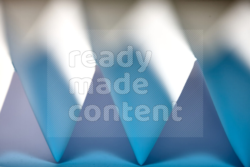 A close-up abstract image showing sharp geometric paper folds in white and blue gradients