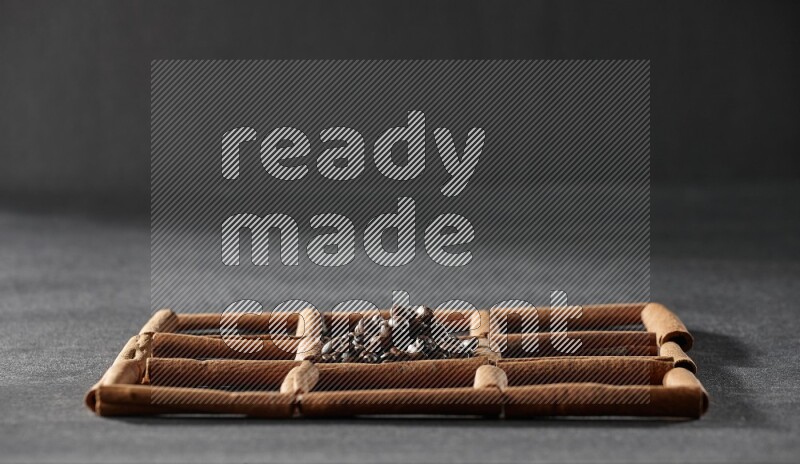 9 مربعات من أعواد القرفة ممتلئة بحبوب القهوة في المنتصف محاطة بجوزة الطيب والنعناع المجفف والقرنفل والريحان المجفف والزنجبيل المجفف والقرفة واليانسون والهيل على أرضية سوداء