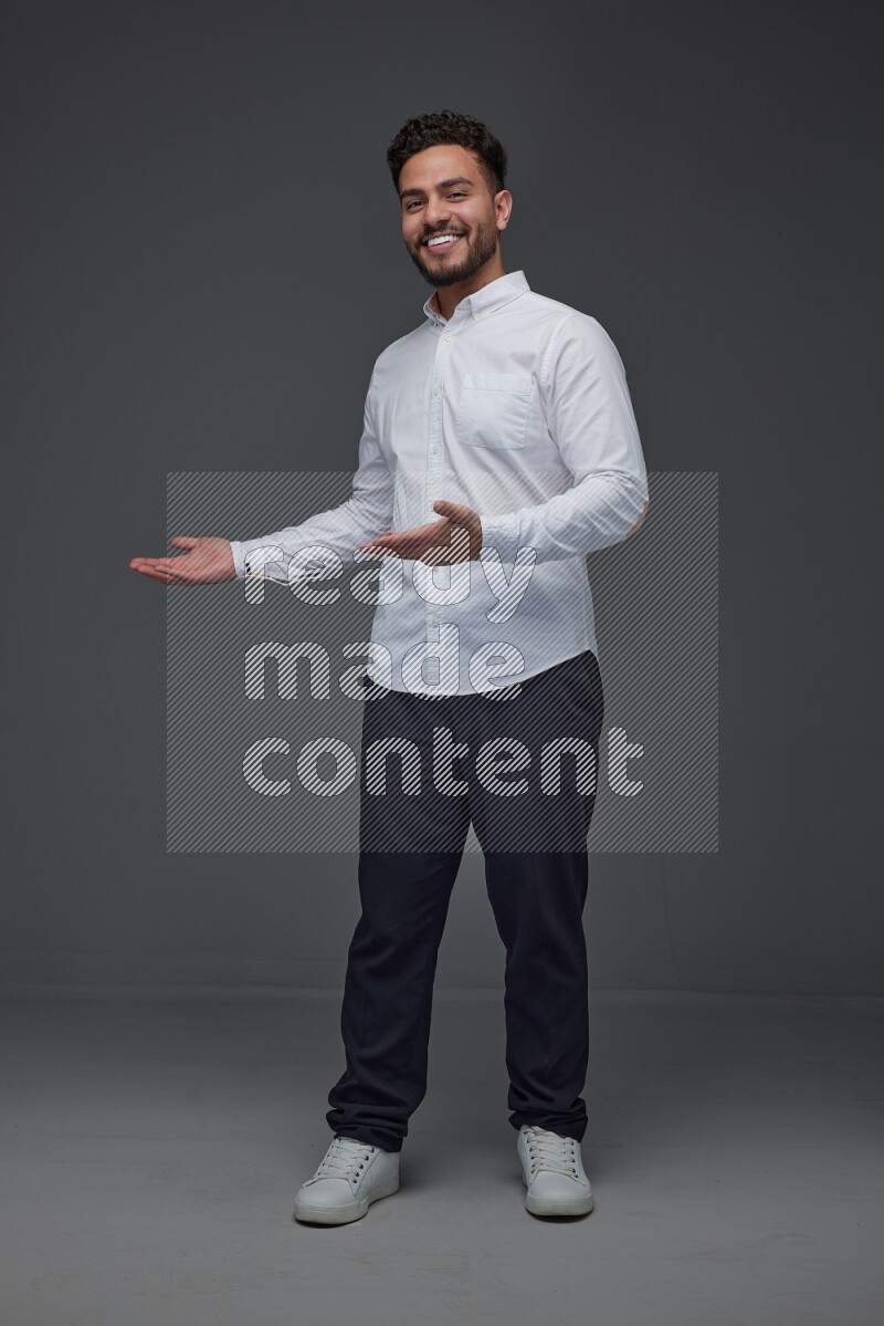 A man wearing smart casual standing and making multi hand gestures eye level on a gray background