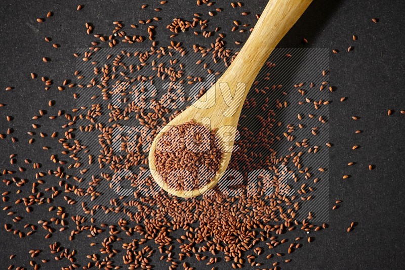 A wooden spoon full of garden cress and seeds spreaded beside it on a black flooring in different angles