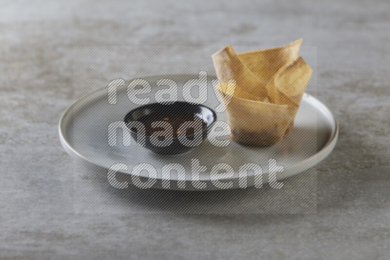 wonton cups with soy sauce ramkin on grey ceramic plate on grey textured counter top