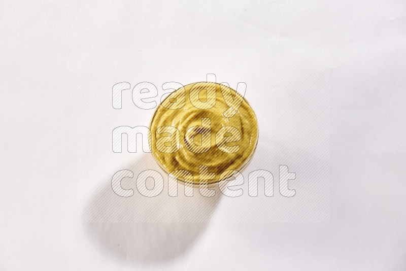 A glass bowl full of mustard paste on a white flooring
