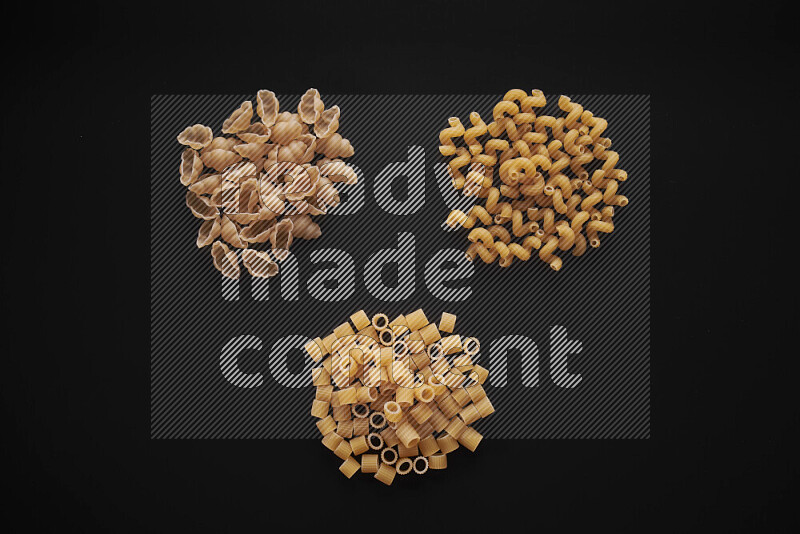 Different pasta types in bunches on black background