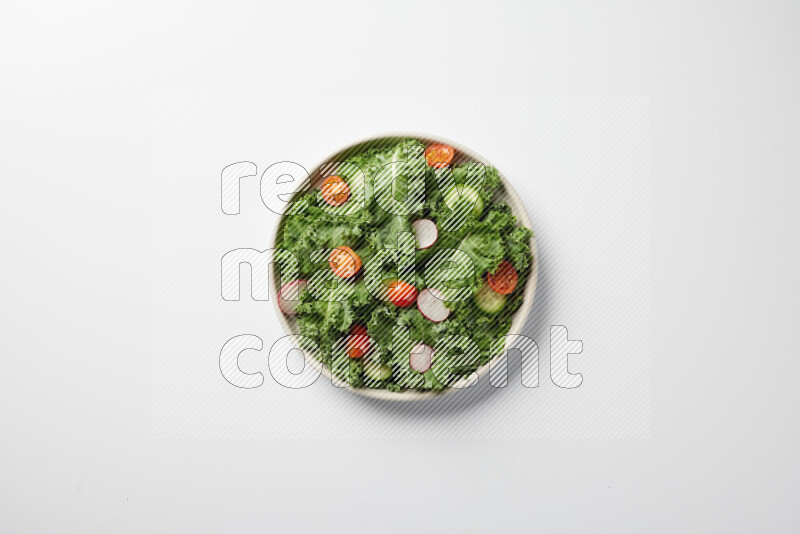 A bowl of fresh vegetables salad with kale leaves, cherry tomatoes, sliced radishes and sliced cucumber on a white background