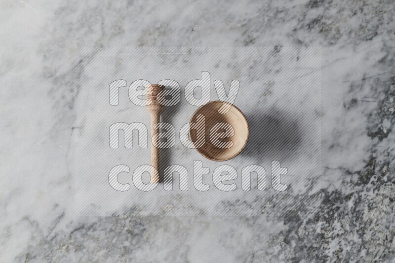 Beige pottery bowl with wooden honey dipper on the side on grey marble background