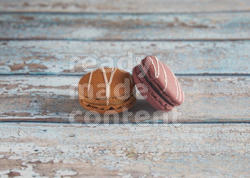 45º Shot of of two assorted Brown Irish Cream, and Red Poppy Flower macarons  on light blue background