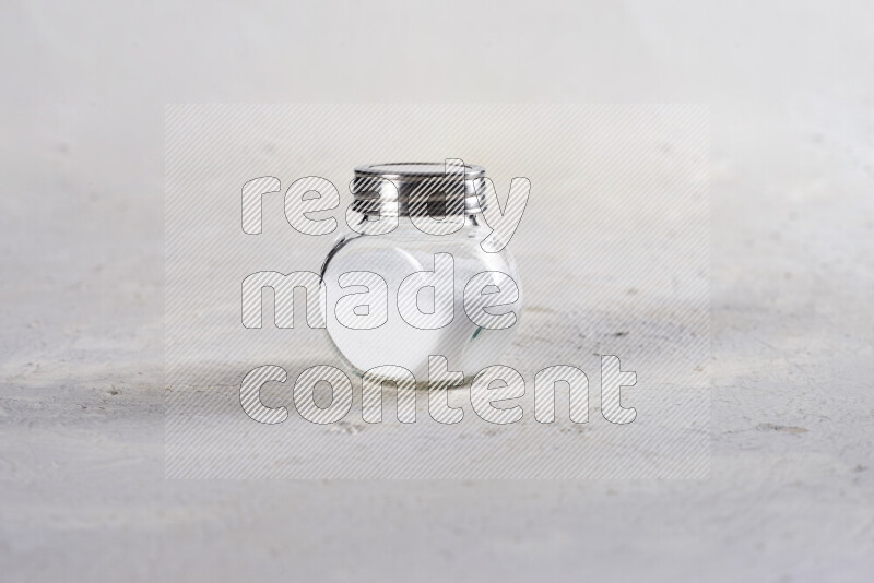 A glass jar full of fine table salt on white background