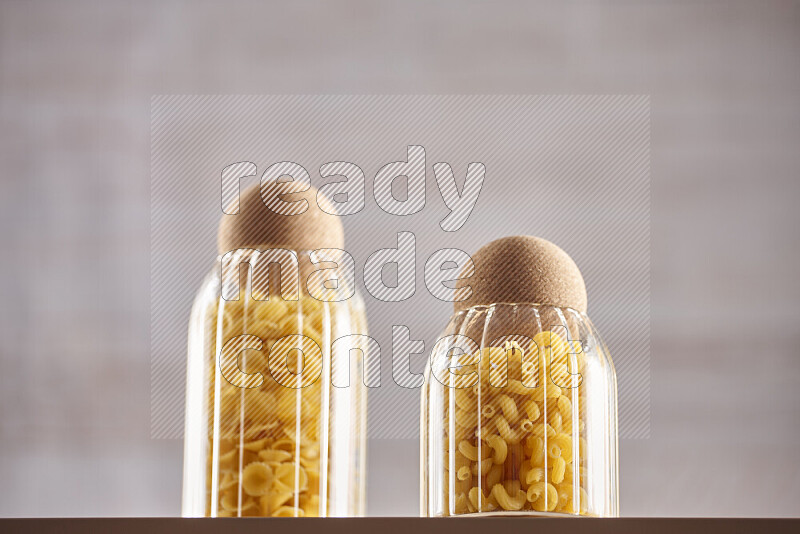 Raw pasta in glass jars on beige background