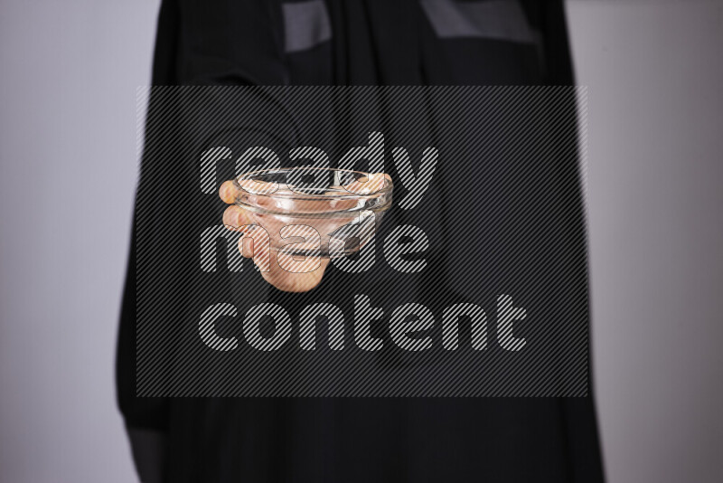 A woman in black abaya holding different glassware in different positions