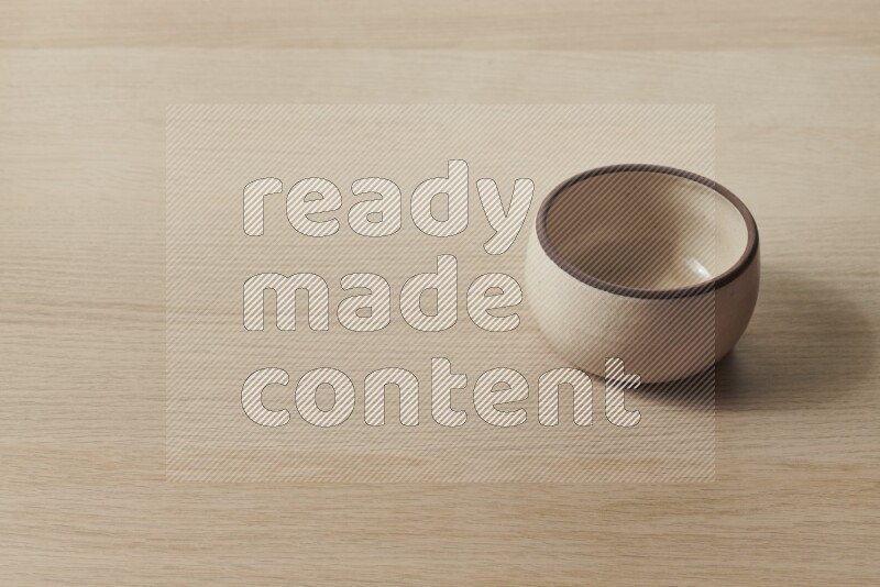 A beige pottery oven bowl on light wooden background