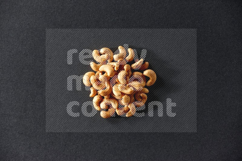 A bunch of cashews on a black background in different angles
