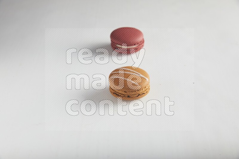 45º Shot of of two assorted Brown Irish Cream, and Red Velvet macarons on white background