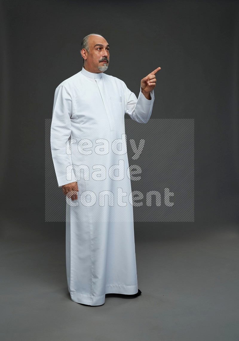 Saudi man without shomag Standing Interacting with the camera on gray background