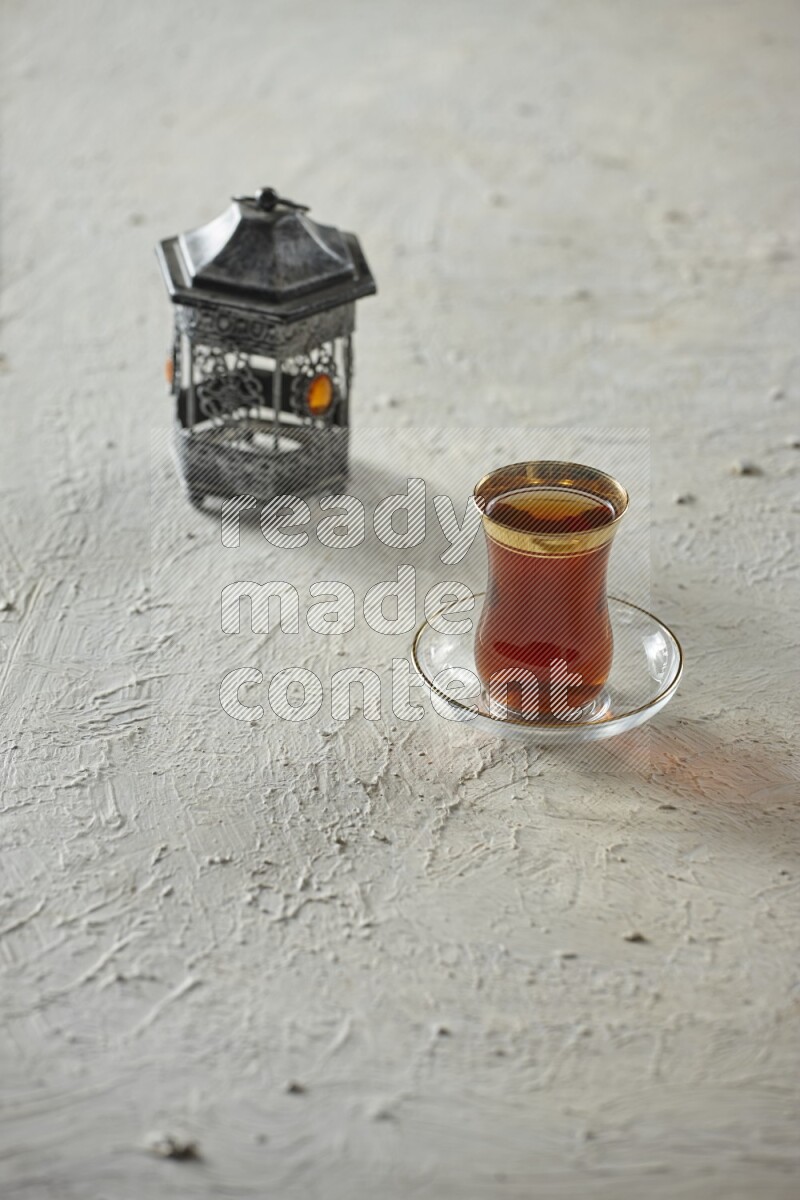 A silver lantern with different drinks, dates, nuts, prayer beads and quran on textured white background