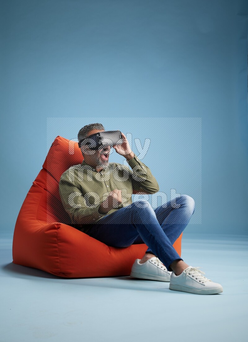 A man sitting on an orange beanbag and gaming with VR