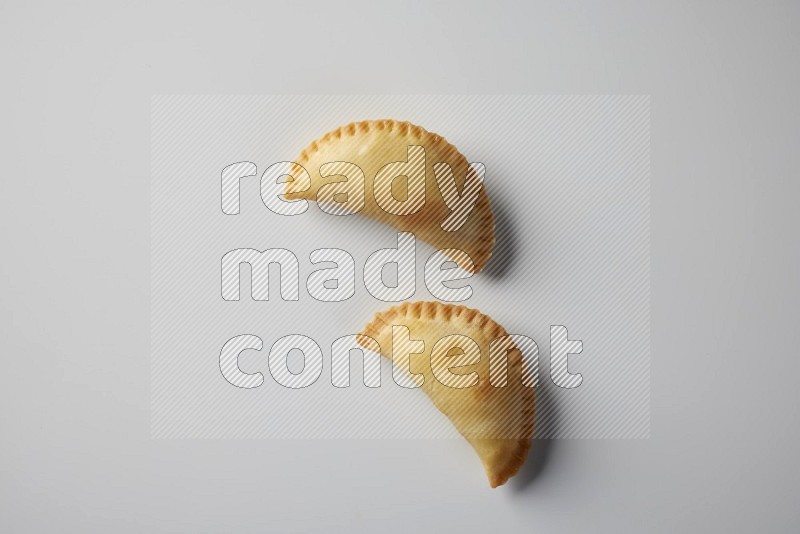 Two fried sambosa from a top angle on a white background