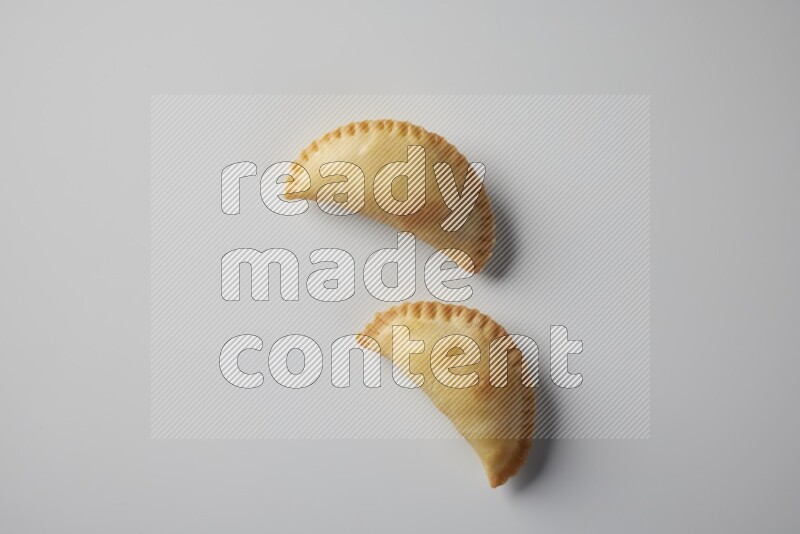 Two fried sambosa from a top angle on a white background