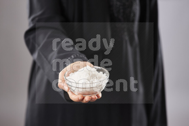 Woman in abaya holding different kinds of spices in different positions