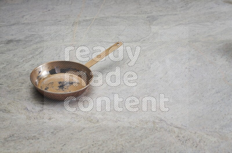 A small copper pan on grey marble background