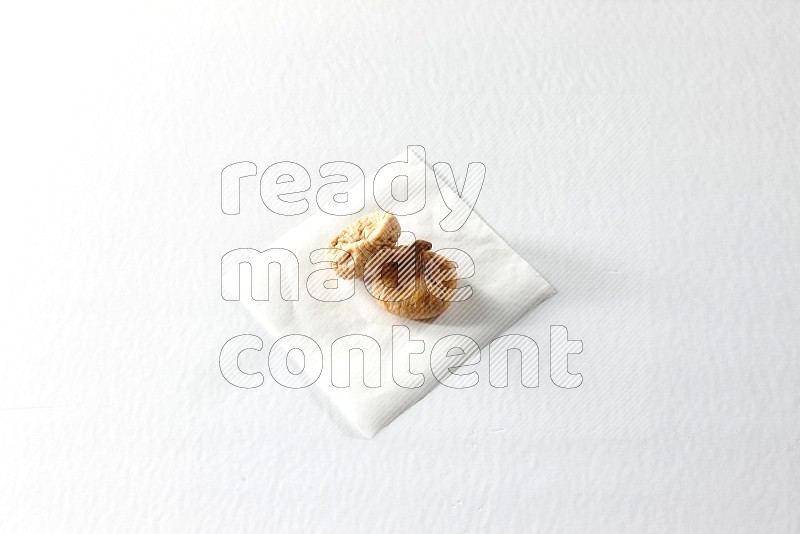 Two dried figs on a piece of paper on a white background in different angles