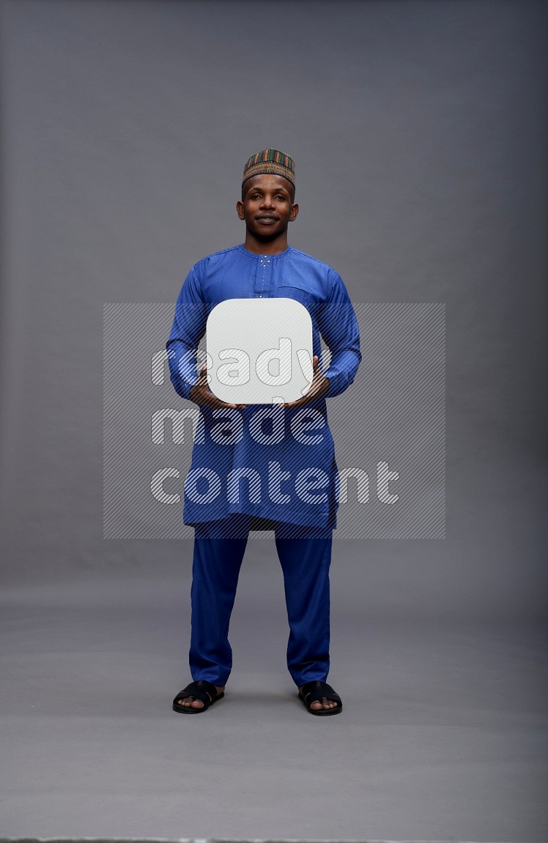 Man wearing Nigerian outfit standing holding social media sign on gray background