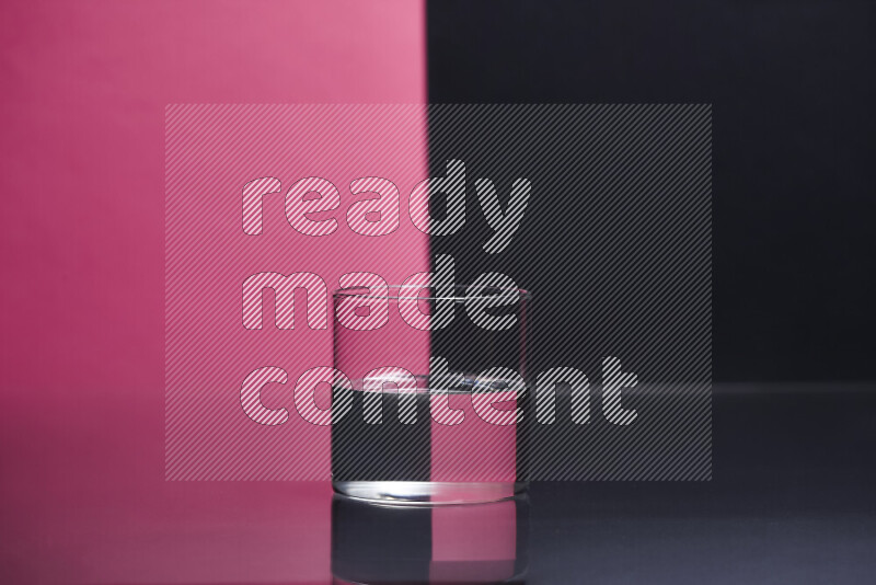 The image features a clear glassware filled with water, set against pink and black background