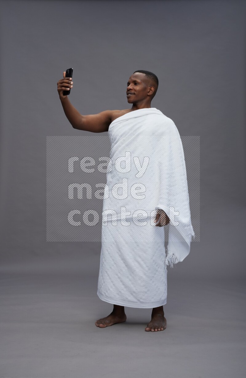 A man wearing Ehram Standing taking selfie on gray background