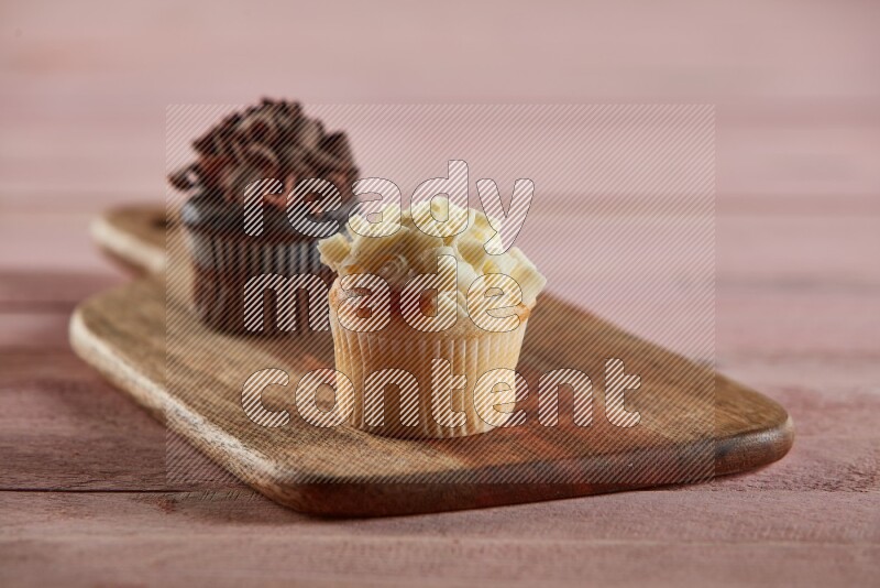 Vanilla mini cupcake topped with white chocolate curls on a wooden board