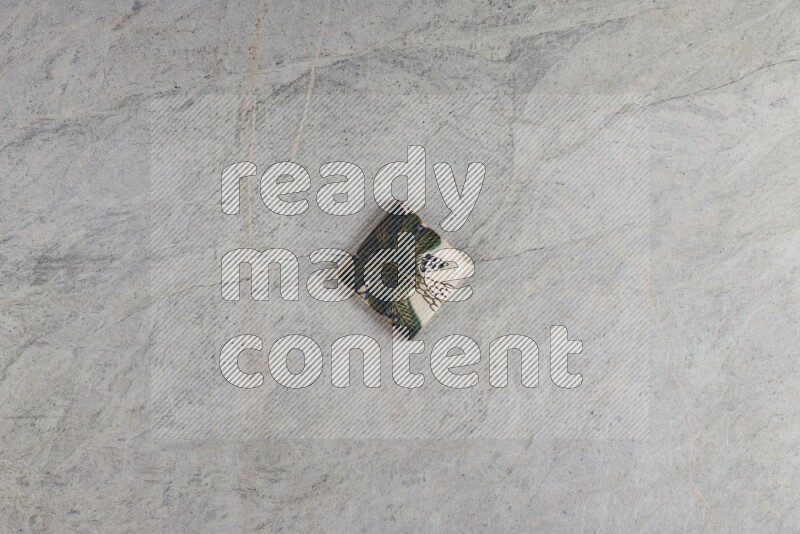 A decorative pottery coaster on grey marble background