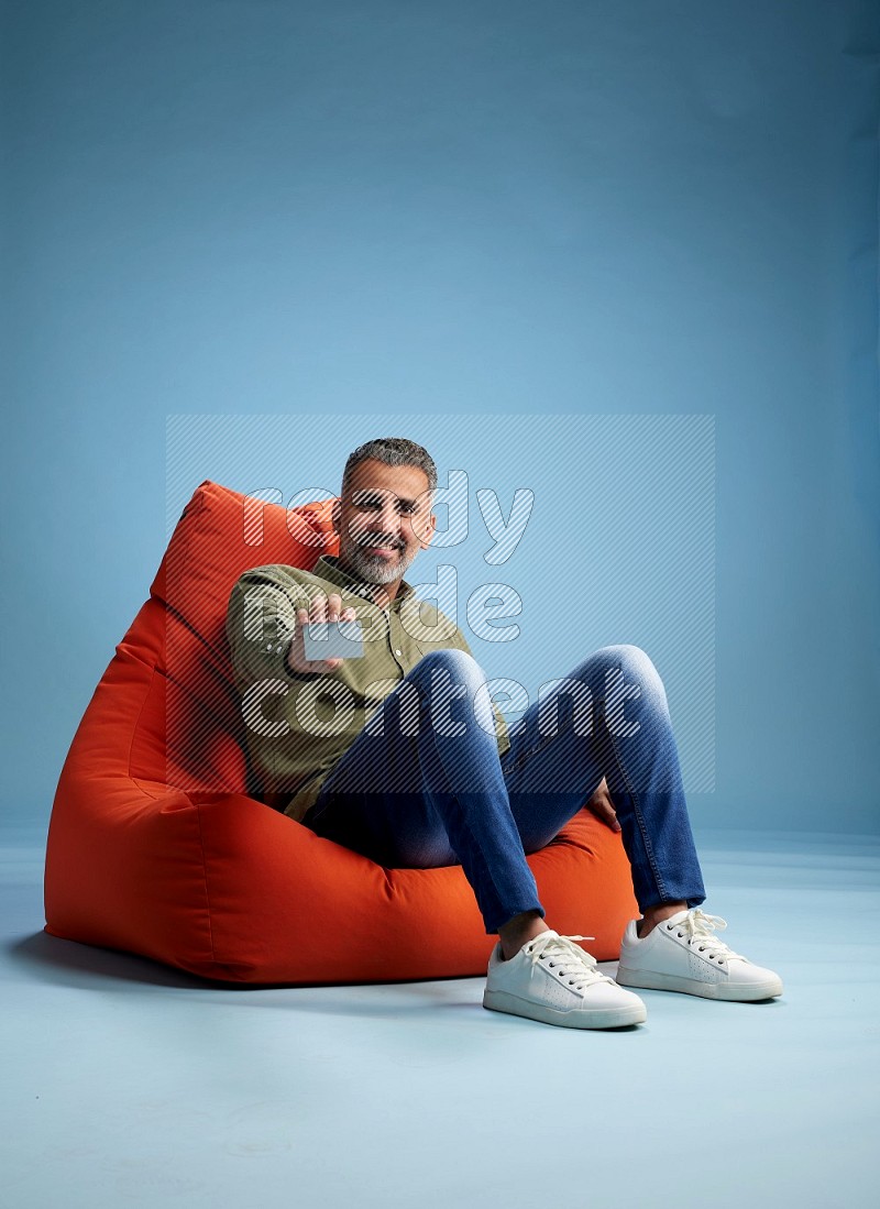 A man sitting on an orange beanbag and holding ATM card