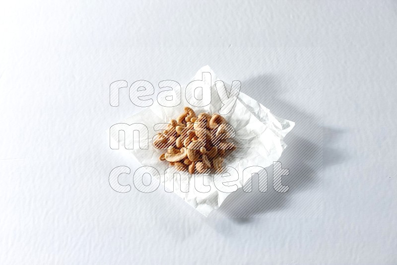 Cashews on a crumpled piece of paper on a white background in different angles