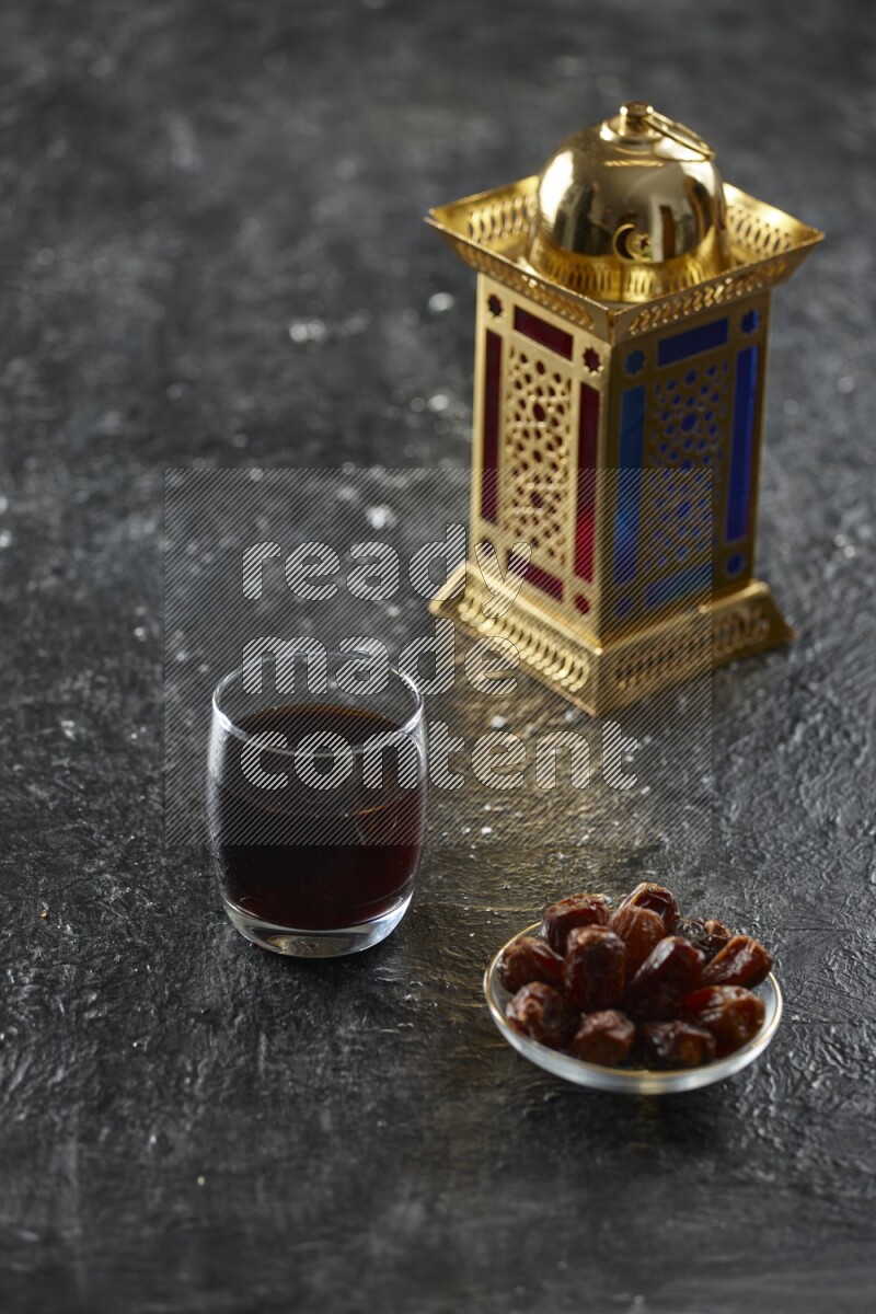 A golden lantern with different drinks, dates, nuts, prayer beads and quran on textured black background