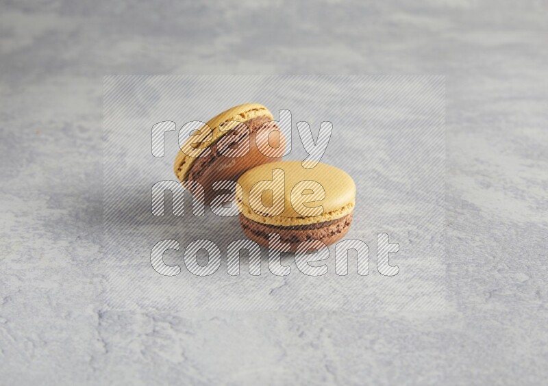 45º Shot of two Yellow and Brown Chai Latte macarons r on white  marble background