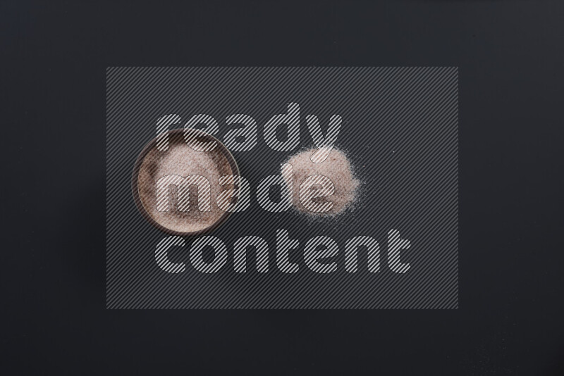 وعاء فخاري ممتلئ بملح الهيمالايا الناعم وملح الهيمالايا الخشن على خلفية سوداء