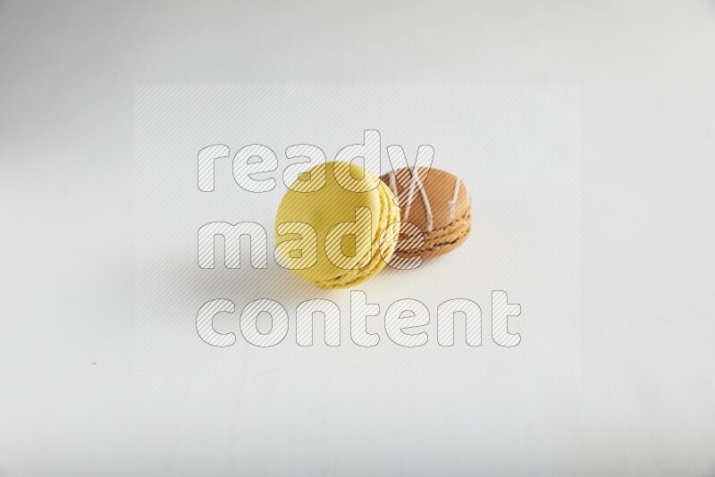 45º Shot of of two assorted Brown Irish Cream, and Yellow Lemon macarons on white background