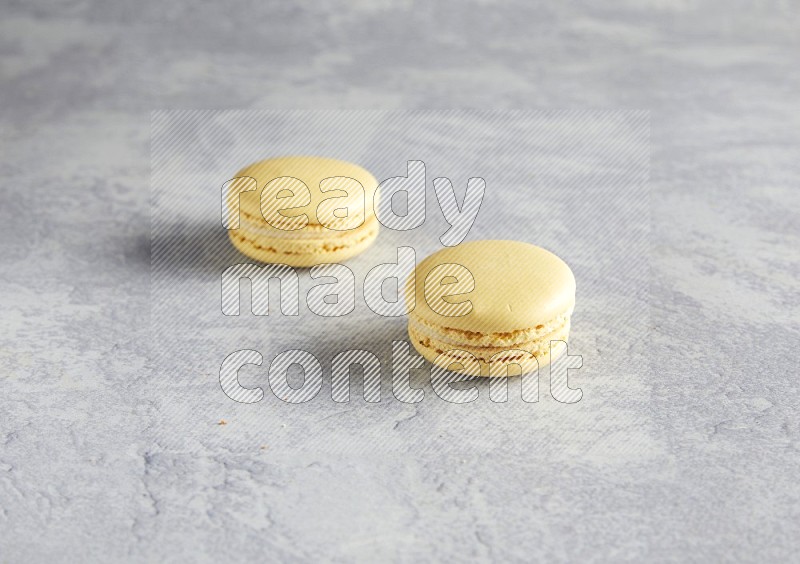 45º Shot of two Yellow Vanilla macarons  on white  marble background