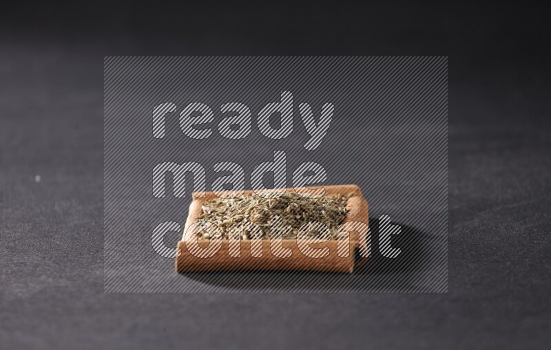 A single square of cinnamon sticks full of cumin on black flooring