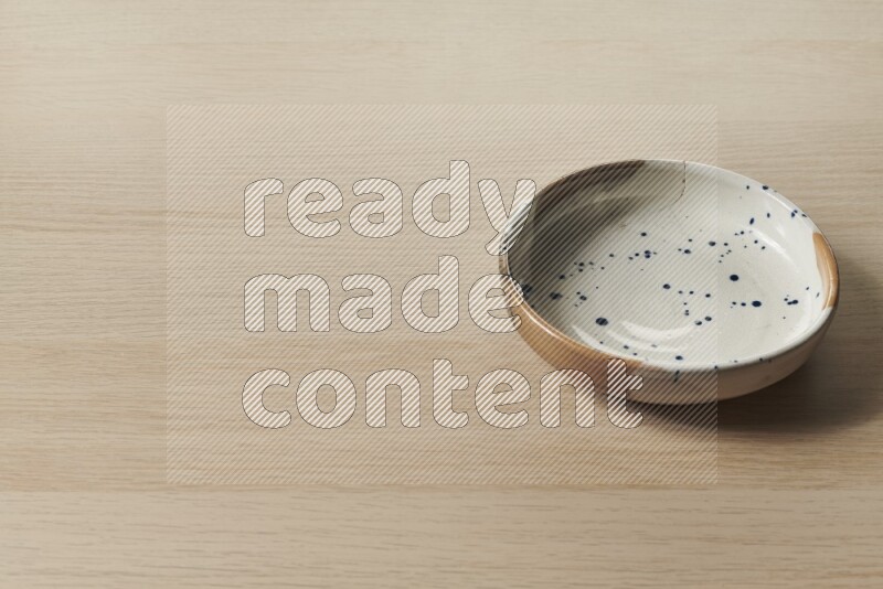 A multicolored pottery bowl on light wooden background