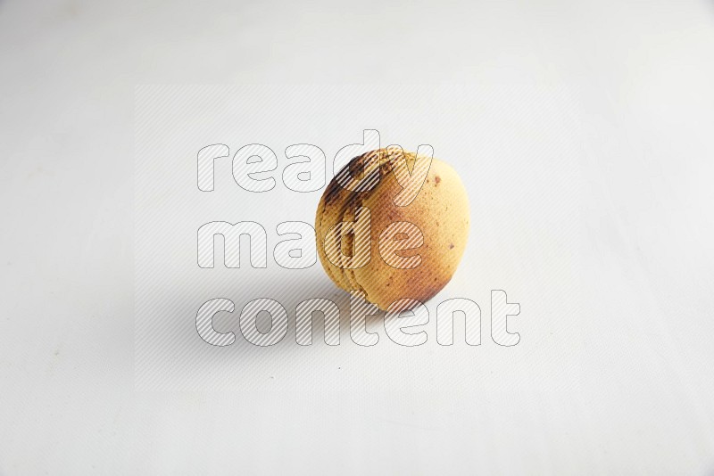45º Shot of Yellow Crème Brulée macaron on white background