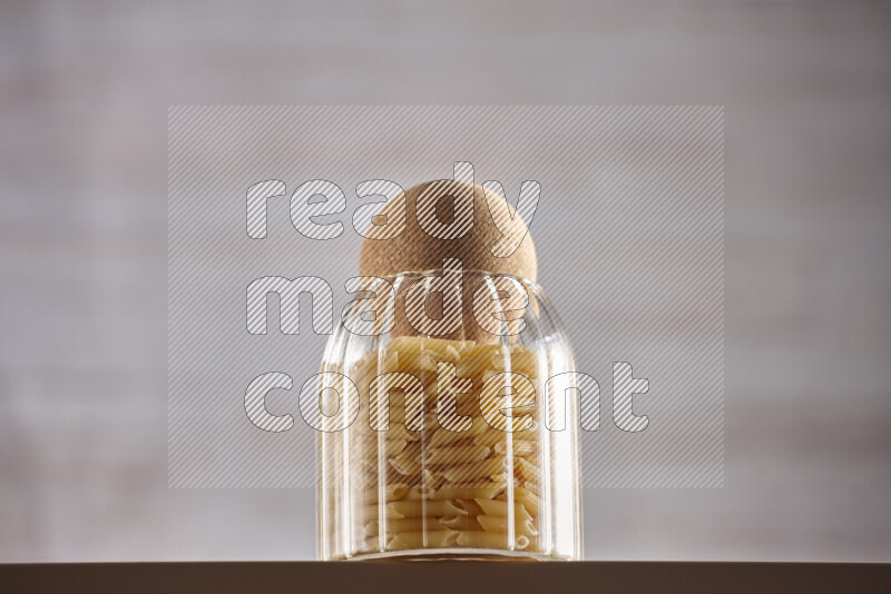 Raw pasta in glass jars on beige background