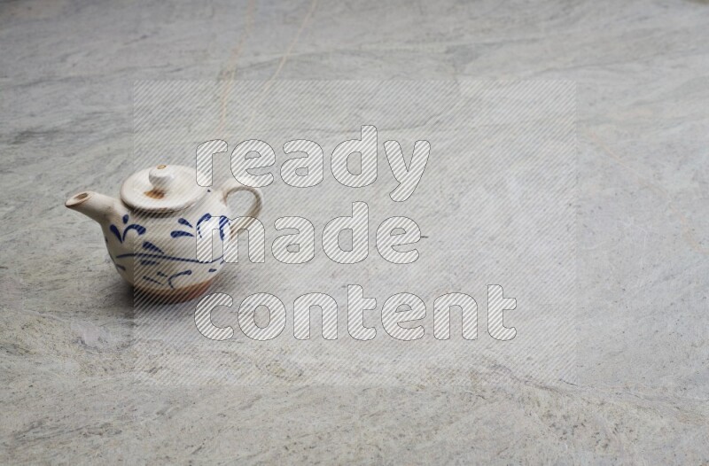 A pottery teapot on grey marble background
